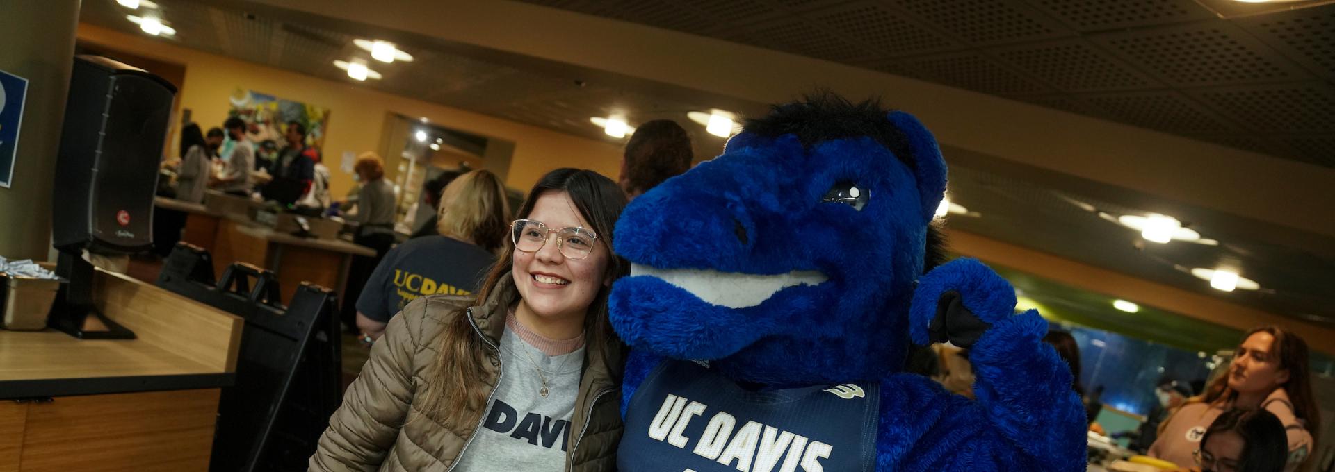 Person standing next to a flexing Gunrock mascot