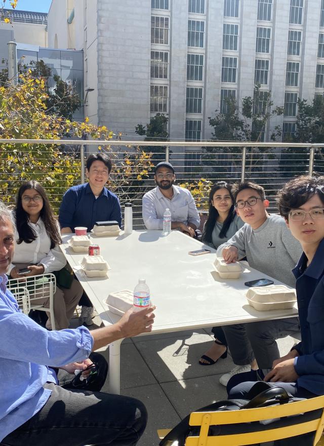 people sitting around a table outside enjoying drinks and food