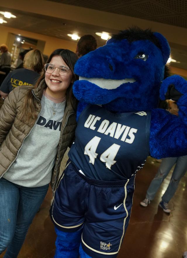 Person standing next to a flexing Gunrock mascot