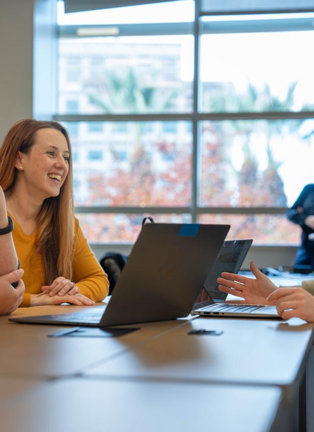 Three Sacramento MBA students chatting in a classroom 