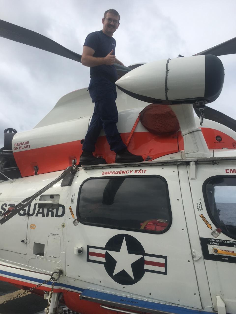 Person standing on top of a parked U.S. Coast Guard helicopter