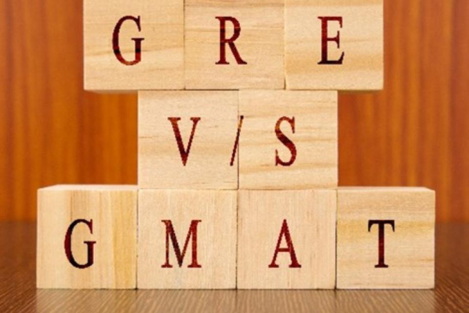 wooden letter blocks stacked on top of each other, spelling out GRE and GMAT